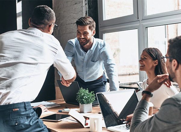 A group of people sitting around a table shaking hands.