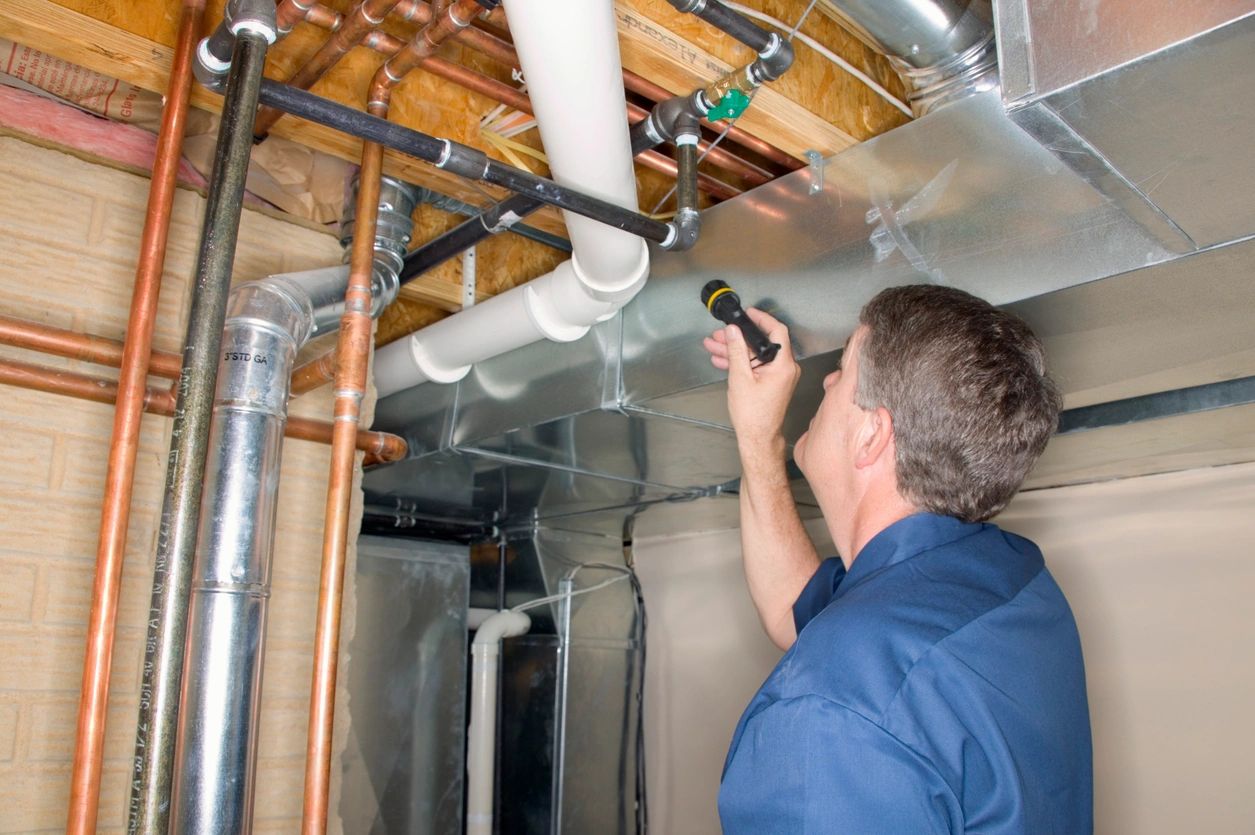 A man is inspecting pipes in an unfinished room.