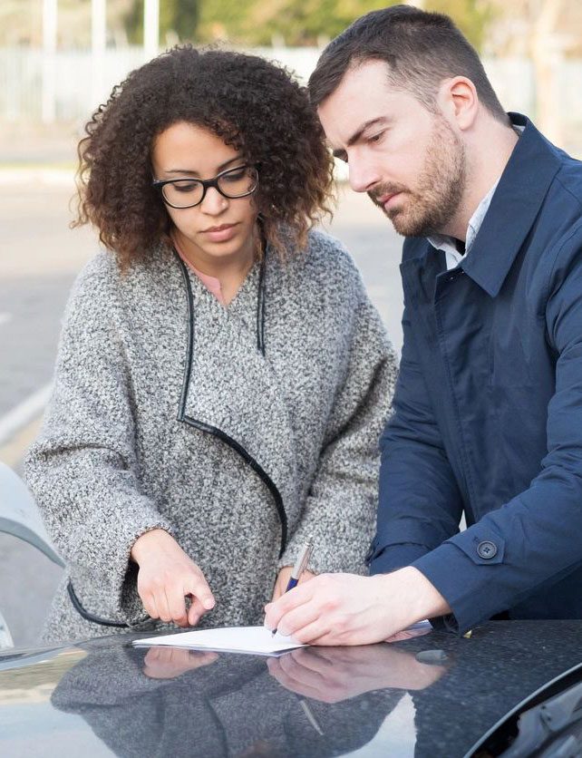 A man and woman signing papers on top of a table.